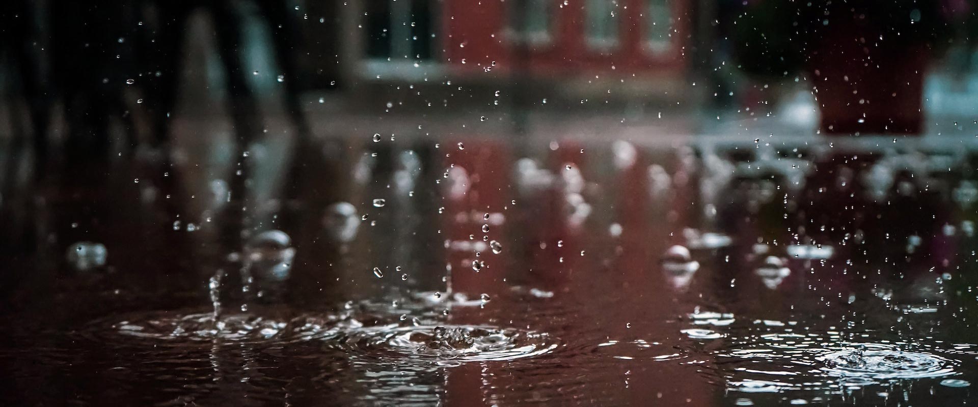A close-up photo of rain and puddles in a city street.
